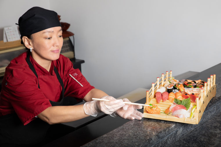 gereltuya souriante, baguettes chinoises à la main, agence un plat de sushis