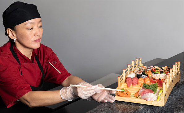 Une cuisinière asiatique prépare un plat à l'aide de baguettes